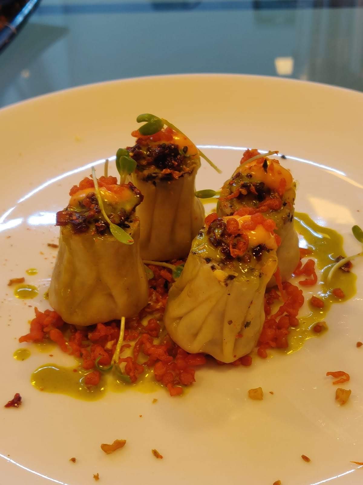 Plated steamed dumplings garnished with sauce and fresh herbs