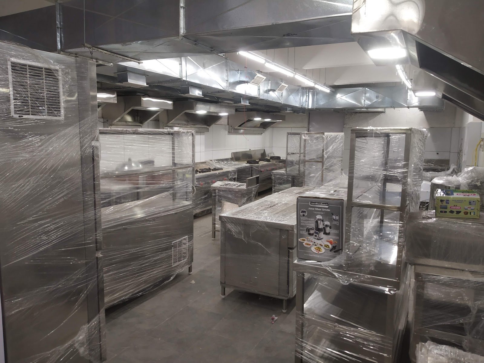 Completed stainless-steel commercial kitchen with ventilation hoods