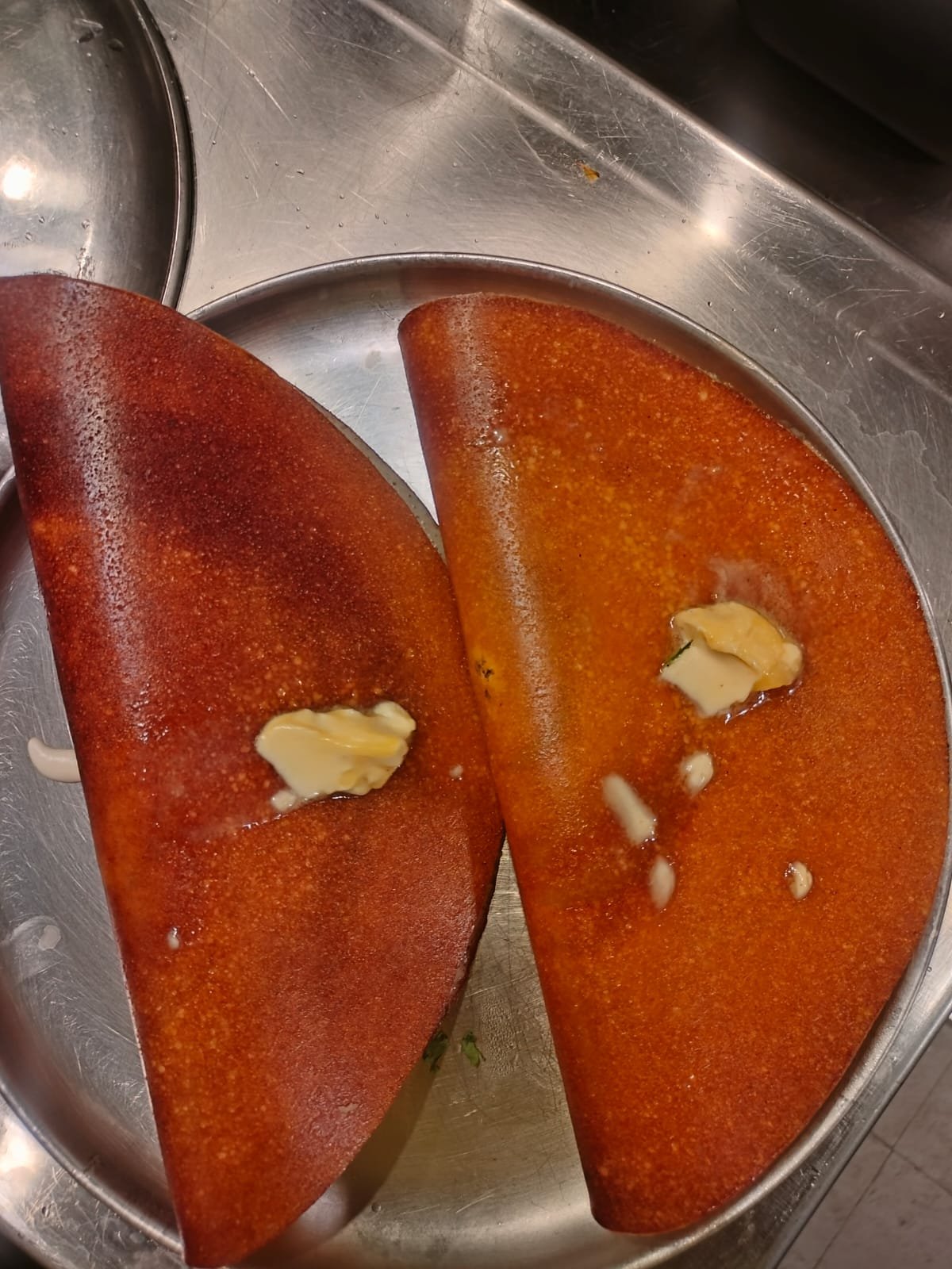 Freshly made dosa served folded on a steel plate